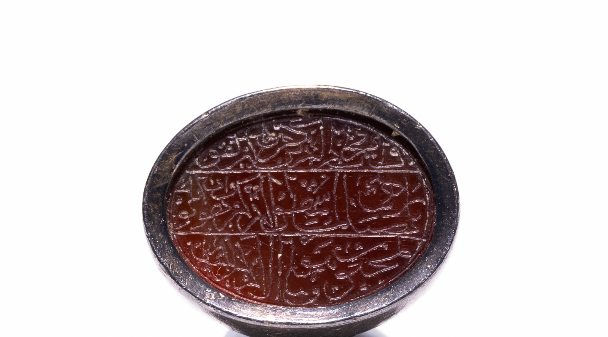 AN ISLAMIC SILVER AND CARNELIAN SIGNET RING WITH ARABIC CALLIGRAPHIC INTAGLIO.