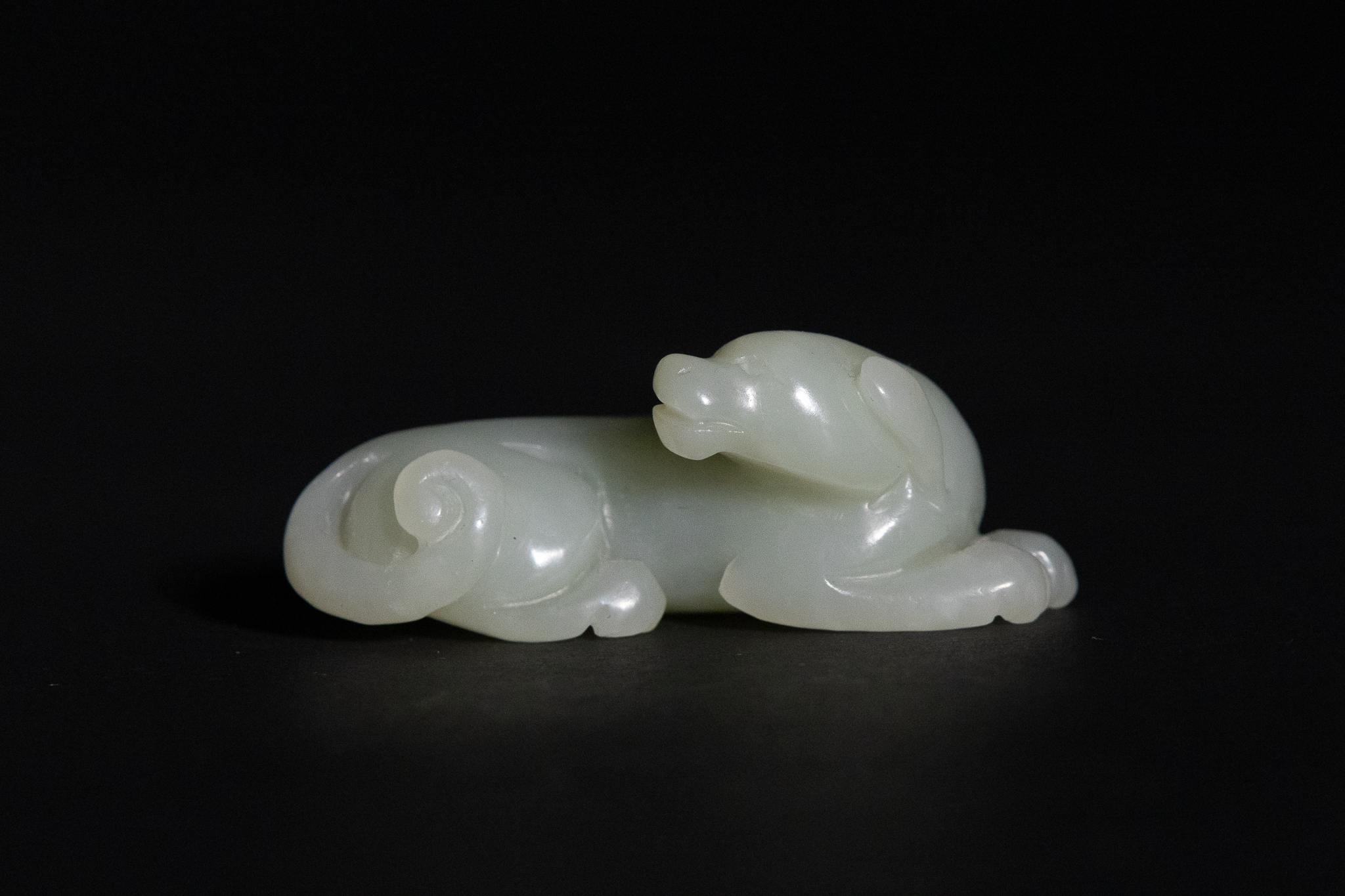 A CHINESE CARVED PALE CELADON JADE FIGURE OF A RECUMBENT HOUND.