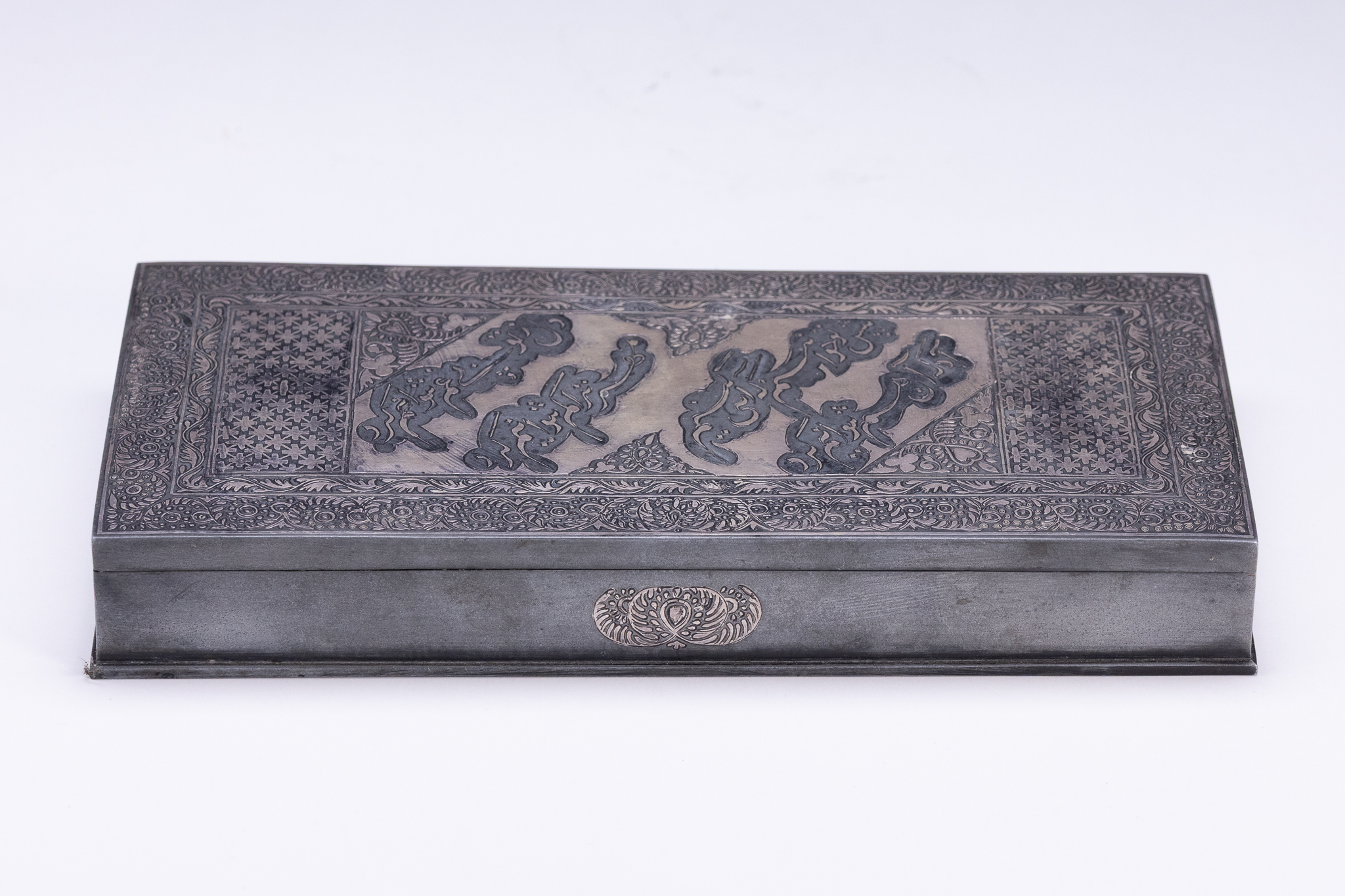 AN IRANIAN ENGRAVED WHITE METAL LIDDED BOX WITH CALLIGRAPHIC DECORATION.