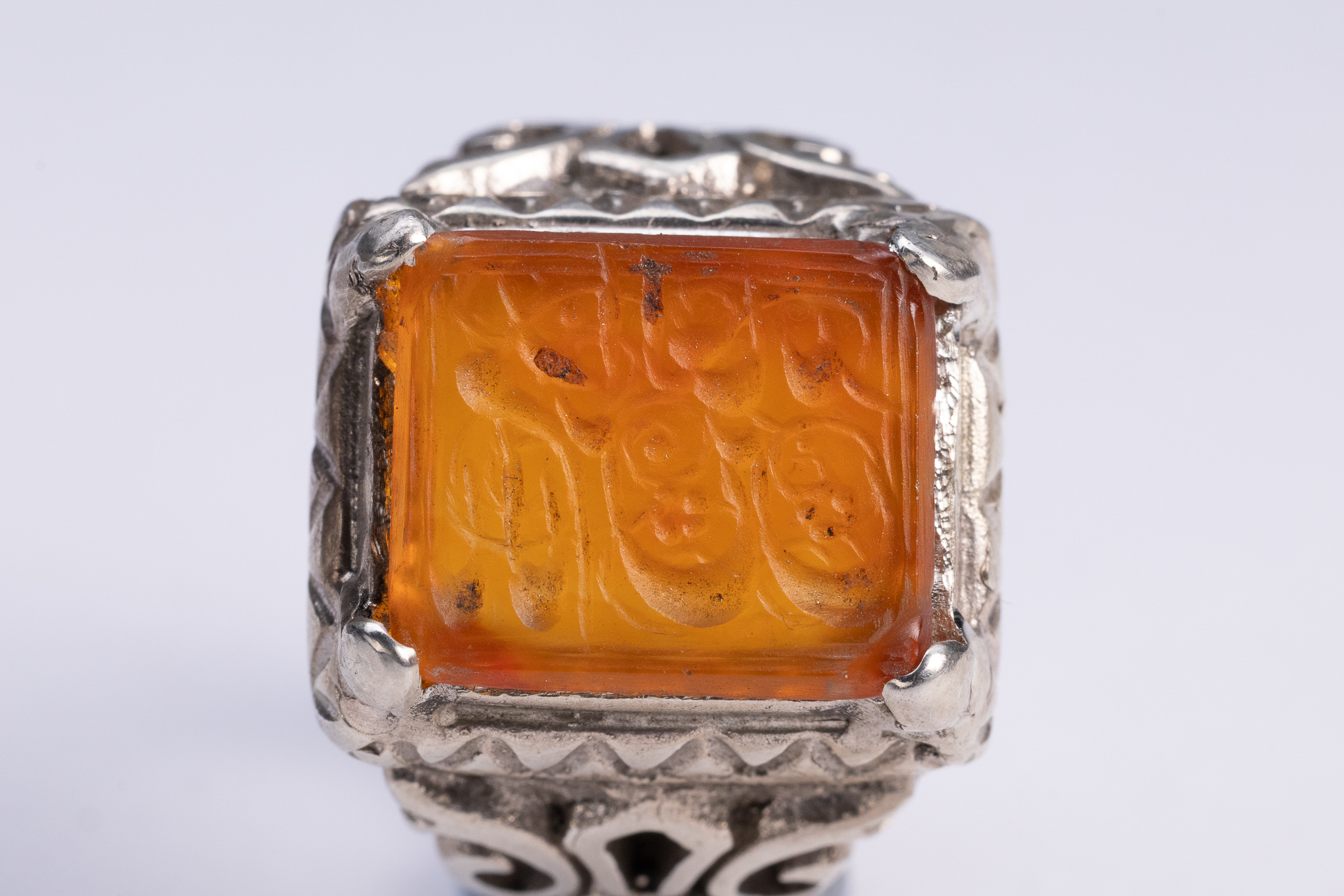 AN ISLAMIC SILVER SIGNET RING WITH INTAGLIO-CARVED CARNELIAN.