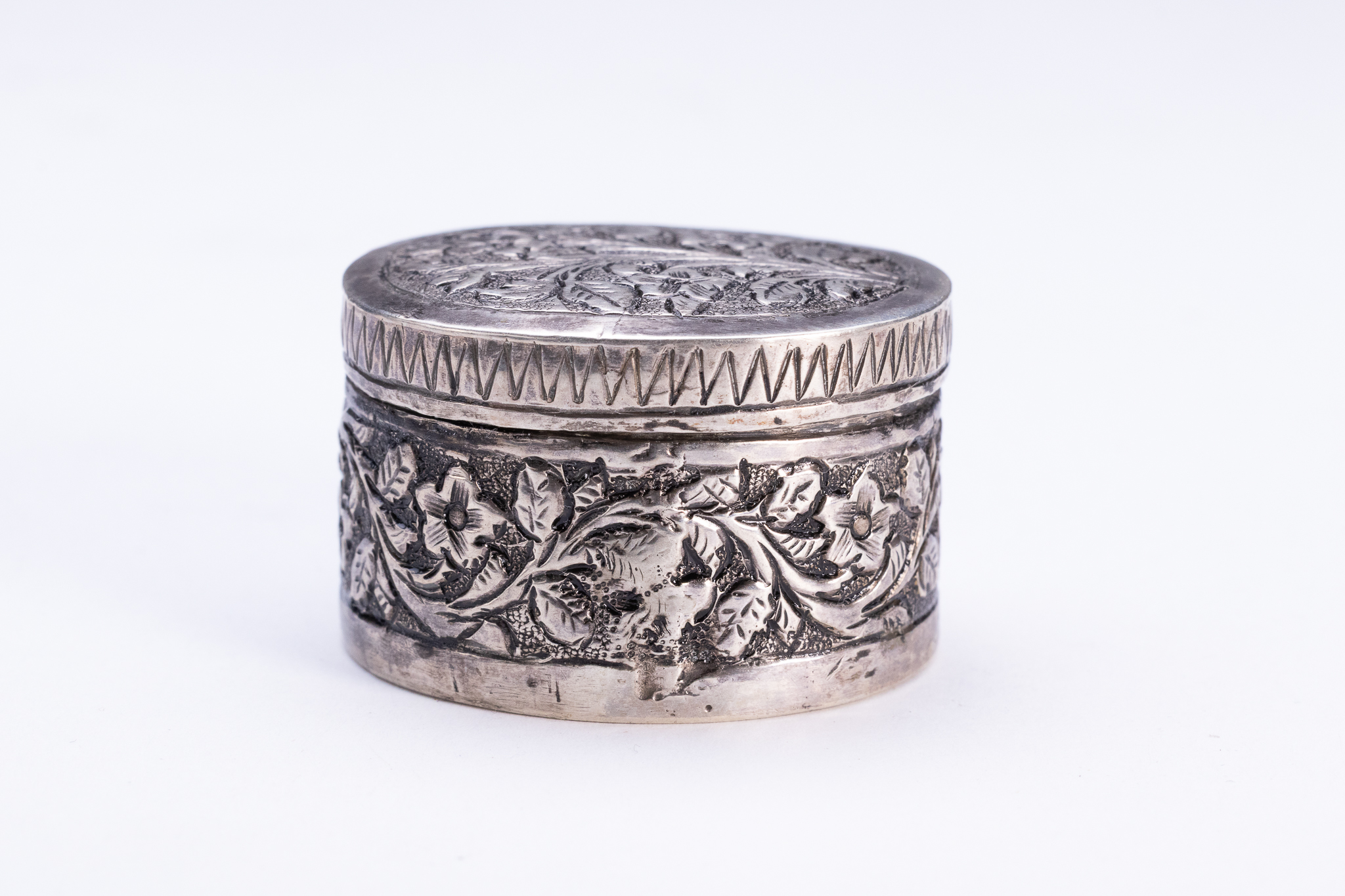 AN INDIAN SILVER REPOUSSE PILL BOX.