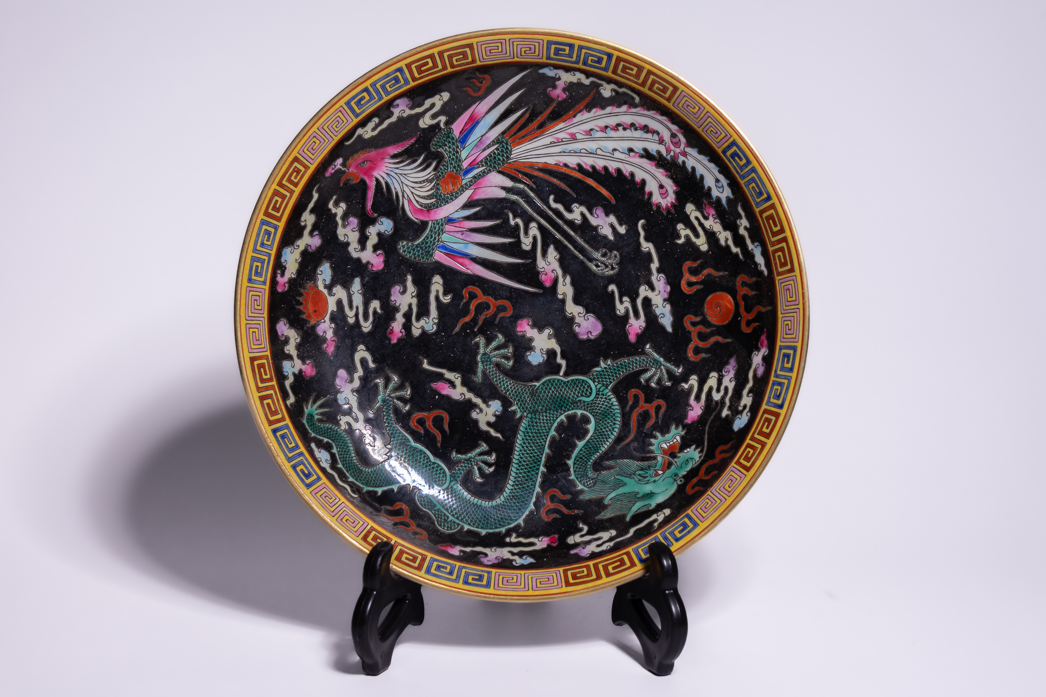 A CHINESE FAMILLE NOIRE PORCELAIN DRAGON AND PHOENIX PLATE, YONGZHENG MARK.