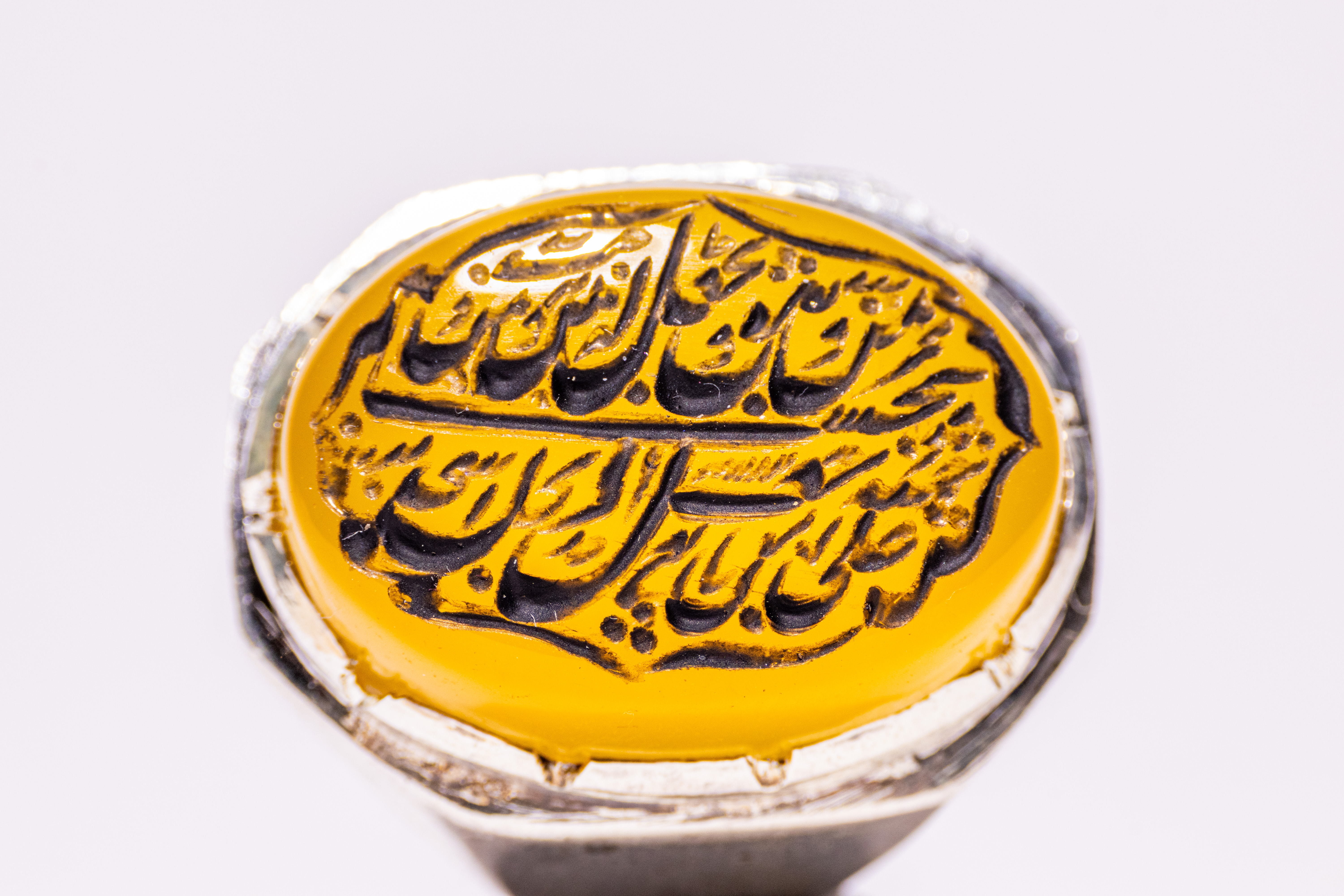 AN ISLAMIC SILVER AND YELLOW AGATE CALLIGRAPHIC SIGNET RING.