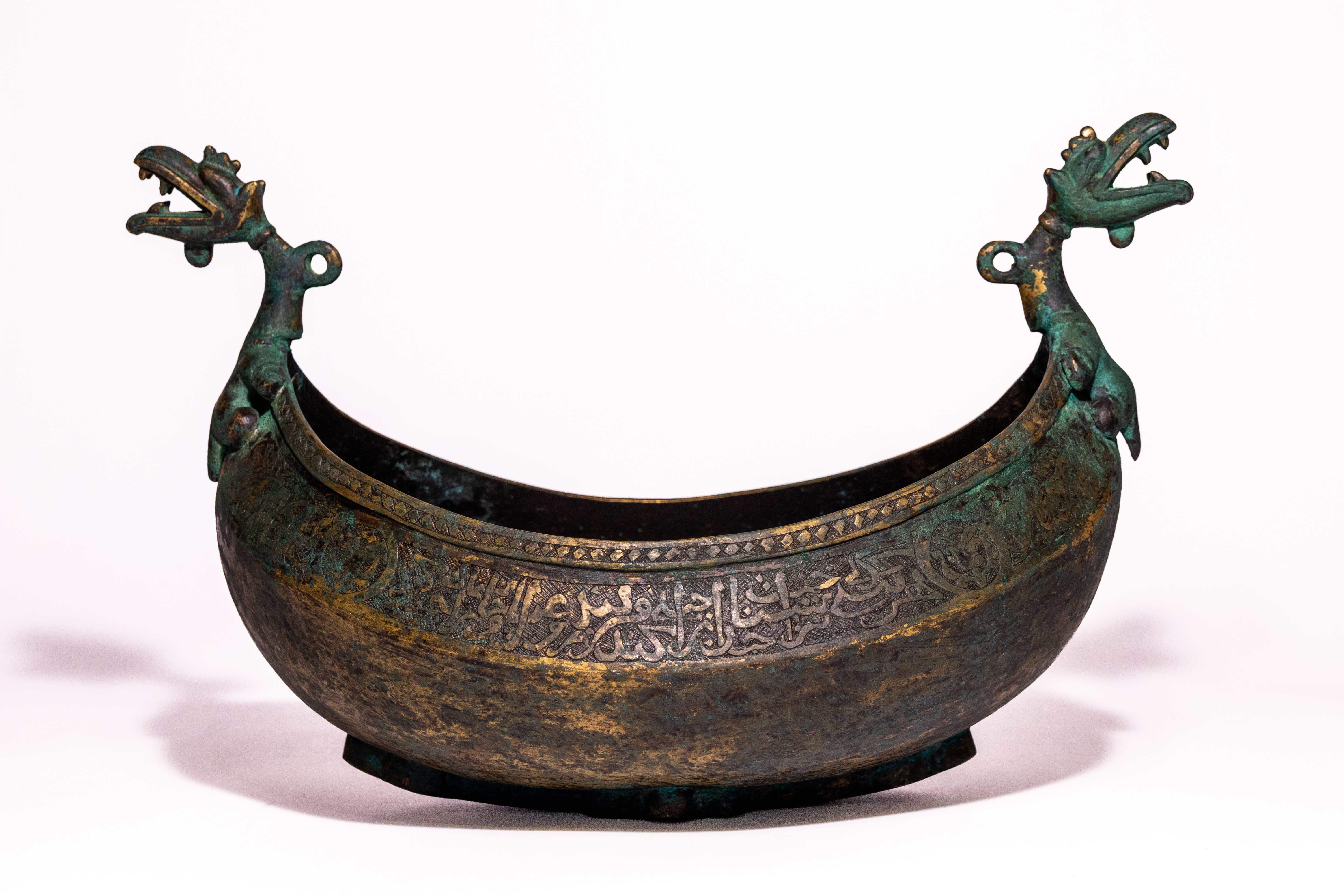 A QAJAR COPPER KASHKUL BEGGING BOWL WITH DRAGON HEAD FINIALS, 19TH CENUTRY.
