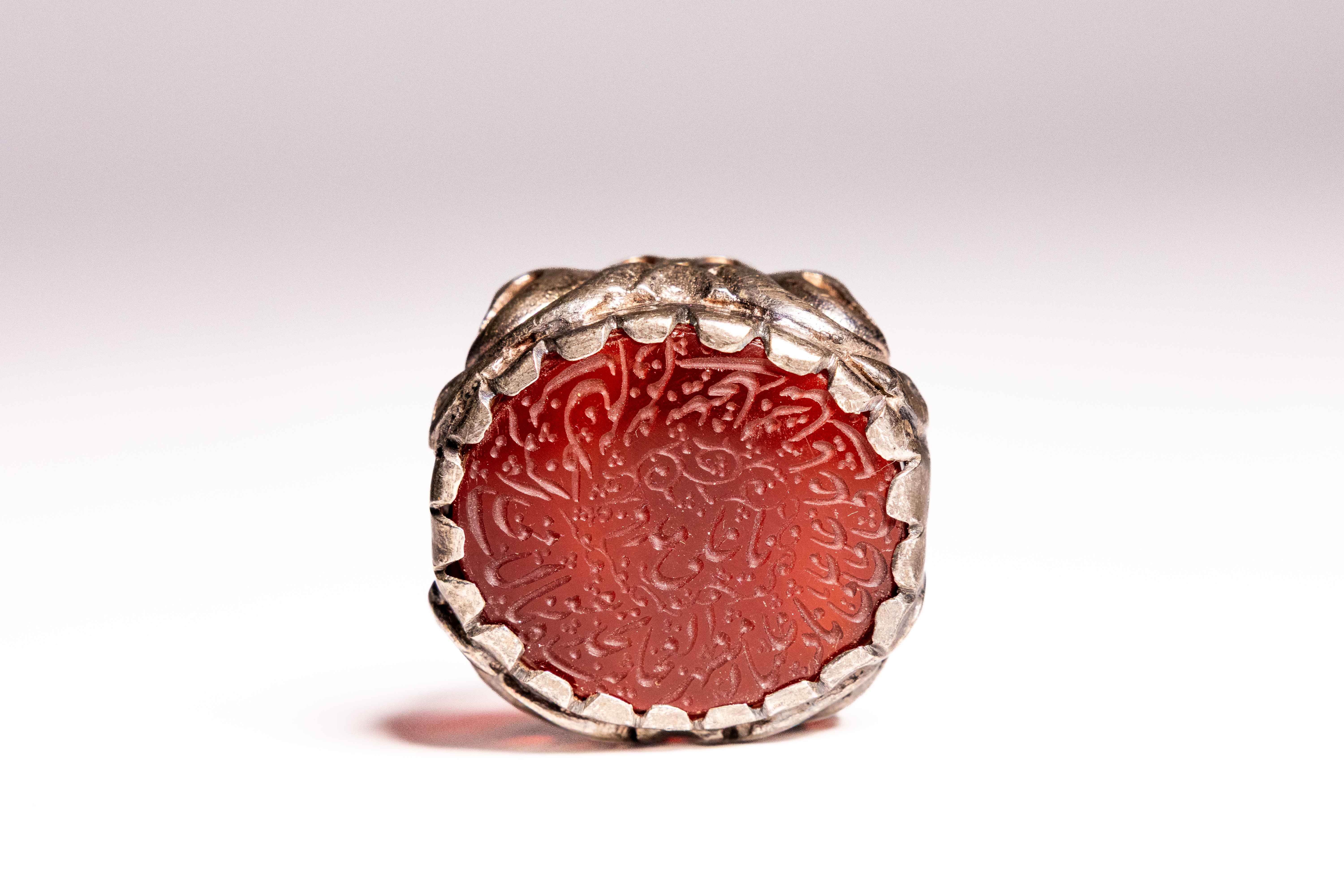 AN ISLAMIC SILVER AND CARNELIAN INTAGLIO CALLIGRAPHIC SEAL RING.