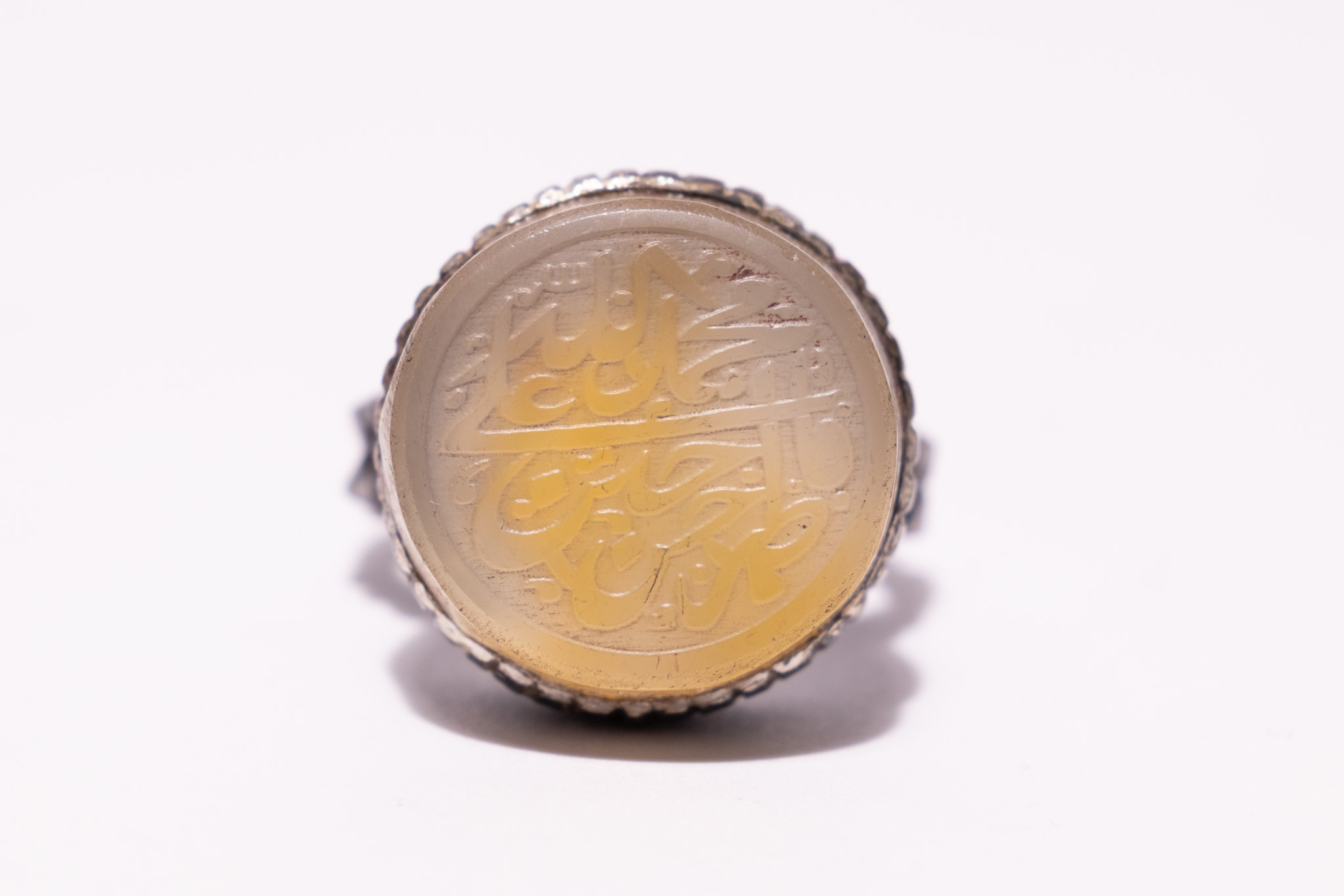 AN ISLAMIC SILVER AND YELLOW AGATE CALLIGRAPHIC INTAGLIO SIGNET RING.