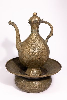 A PERSIAN BRASS EWER AND BASIN SET WITH ENGRAVED DECORATION. The set comprises a ewer of 
