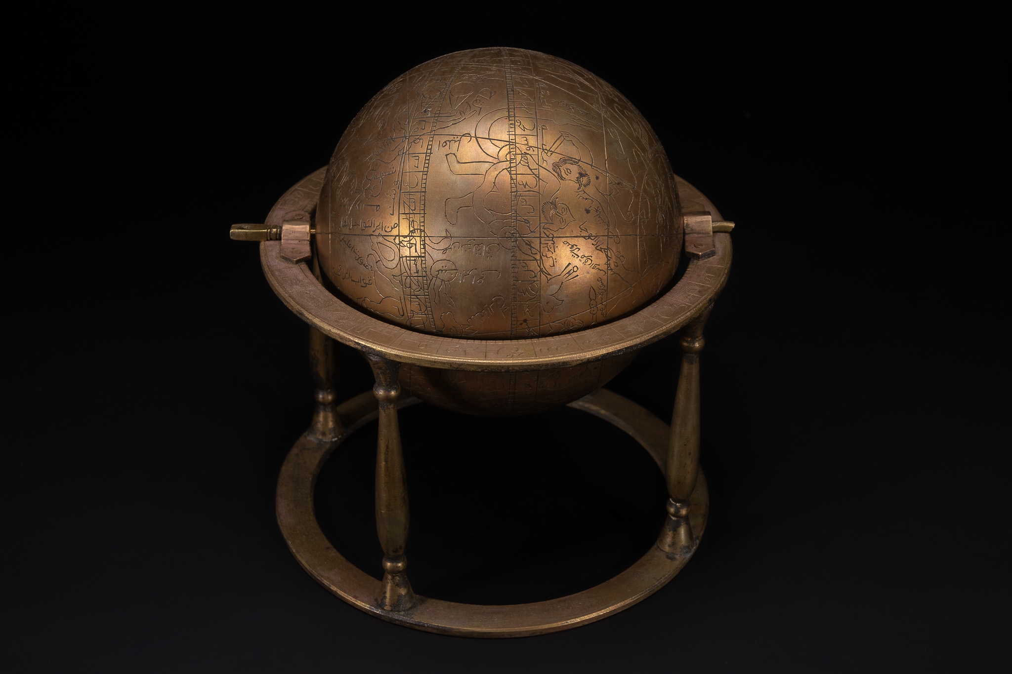 AN ISLAMIC BRASS CELESTIAL GLOBE ON STAND WITH ENGRAVED ZODIAC AND SCRIPT.