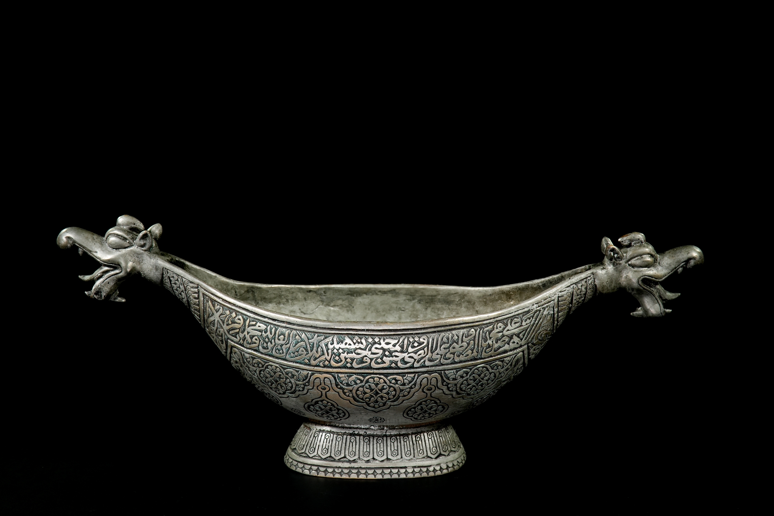 A QAJAR STYLE COPPER KASHKUL WITH DRAGON-HEAD TERMINALS.