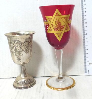 Two Kiddush cups: a. red glass. With gold picture, star of David and face of Moses height 18 cm 