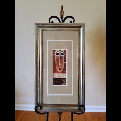 Framed Tribal Mask Art. Home decor item features a tribal mask art in a decorative frame. 
