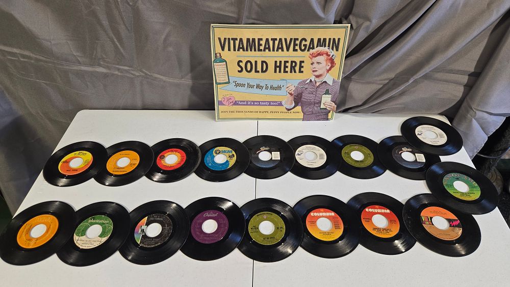 Lot 3: (18) vintage 45 records and Lucy metal sign