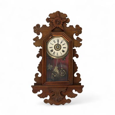 RELÓGIO DE PAREDE. Caixa em madeira de mogno entalhada com enrolamentos e estrela central 