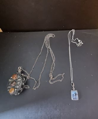 Two necklaces one is a 
Perfume bottle and the 
Other is platinum plated