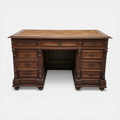 DESK. Carved solid wood desk with brass fittings. Two pedestals with drawers. Leather-topped 