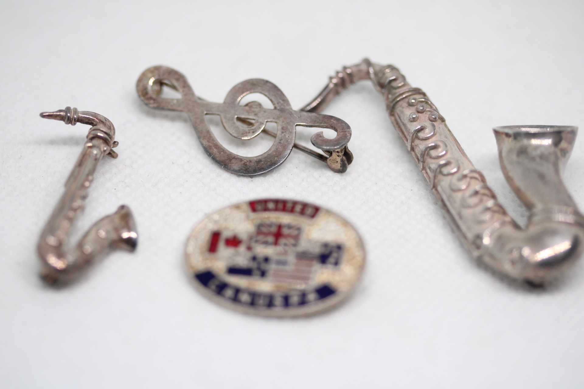 2x Silver brooch in the form of saxophones, note silver brooch & 1 other