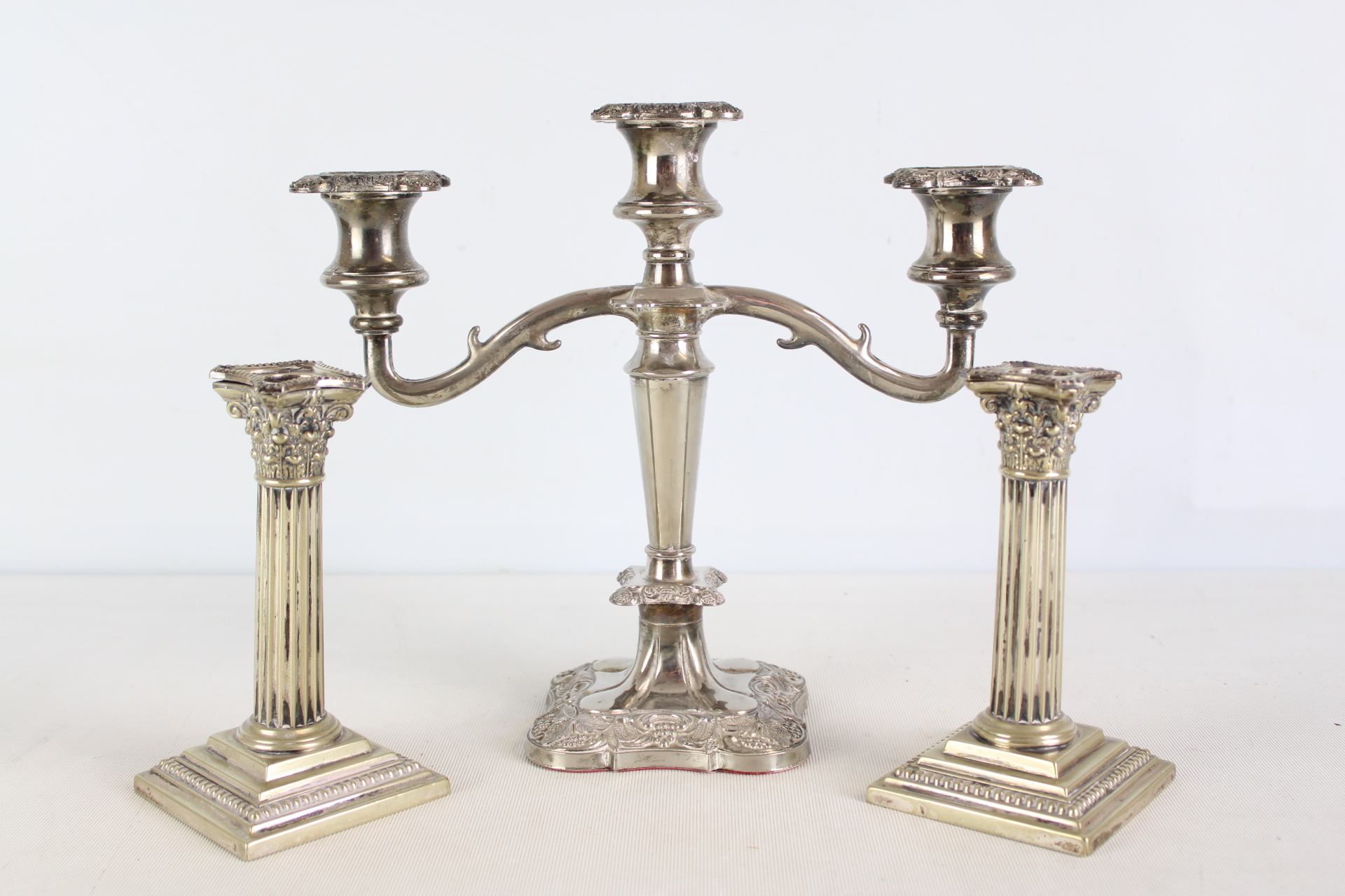A Trio of Silver-Plated Table Lights Including a Three-Light Candelabra and a Pair of Corinthian Column Candlesticks