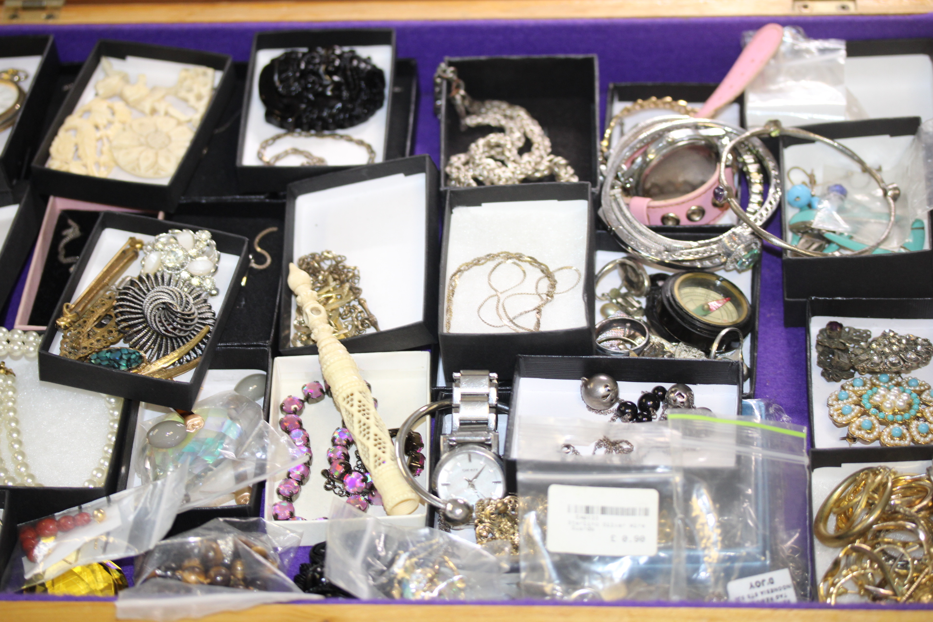 Large collection of unsorted jewellery to include some silver in display case