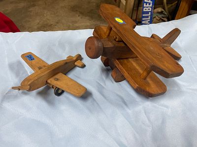 Creative Playthings Wooden Toy Airplane. A light brown wooden toy airplane with black wheels 