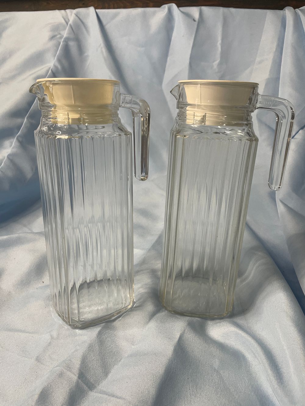 Lot 299: Two Clear Fluted Glass Pitchers with Plastic Lids