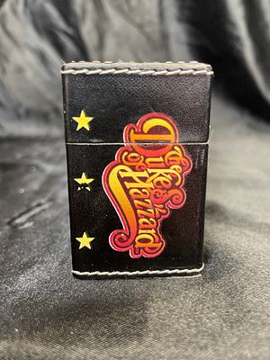 A 2007 Warner Bros. Entertainment Dukes of Hazzard Flip-Top Lighter. A rectangular, hinged 