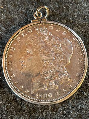 1889 Morgan Silver Dollar Coin Pendant. A silver-toned 1889 Morgan Silver Dollar coin featuring 