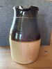 Two-Tone Brown and Tan Stoneware Pottery Pitcher. A two-tone stoneware pitcher featuring a dark Image - 1