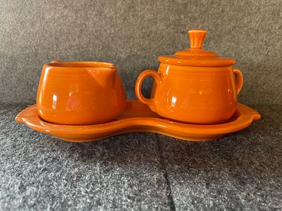 A bright orange Fiesta ceramic creamer and sugar set. A bright orange ceramic set featuring a 