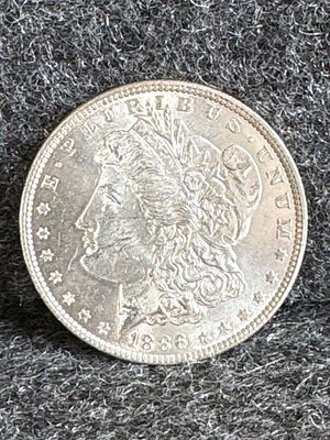 1886 Morgan Silver Dollar Coin. A silver-toned 1886 Morgan silver dollar coin featuring Liberty 