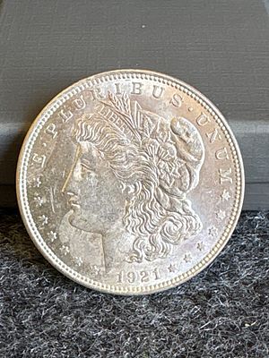 1921 Morgan Silver Dollar. A silver-colored 1921 Morgan silver dollar featuring Liberty on the 