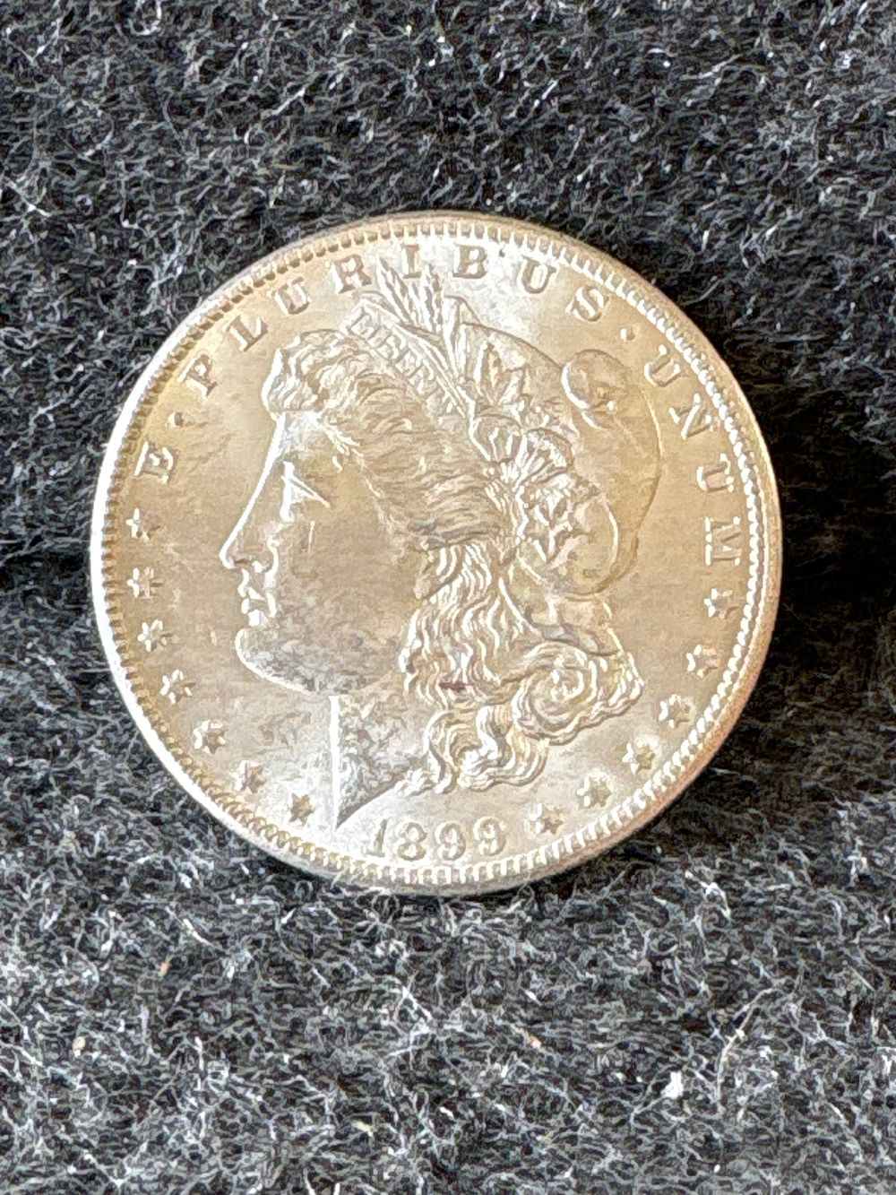 1899 Morgan Silver Dollar Coin. A silver 1899 Morgan silver dollar coin featuring Liberty on the 