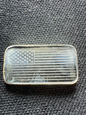 1 Gram .999 Fine Silver Bar with American Flag Motif. A single rectangular silver bullion bar. 