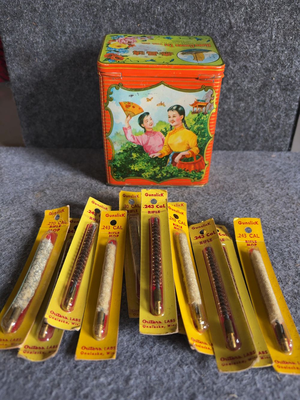 Lot 165: A Group of Vintage Gunslick Rifle Cleaning Accessories and a Hong Kong Tea Tin