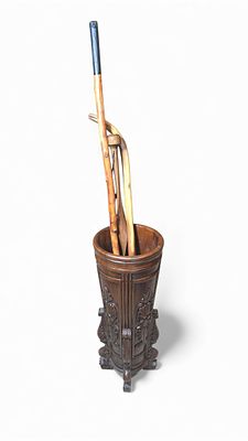 A Carved Wooden Umbrella/Cane Stand with Three Assorted Walking Canes. A dark-stained carved 