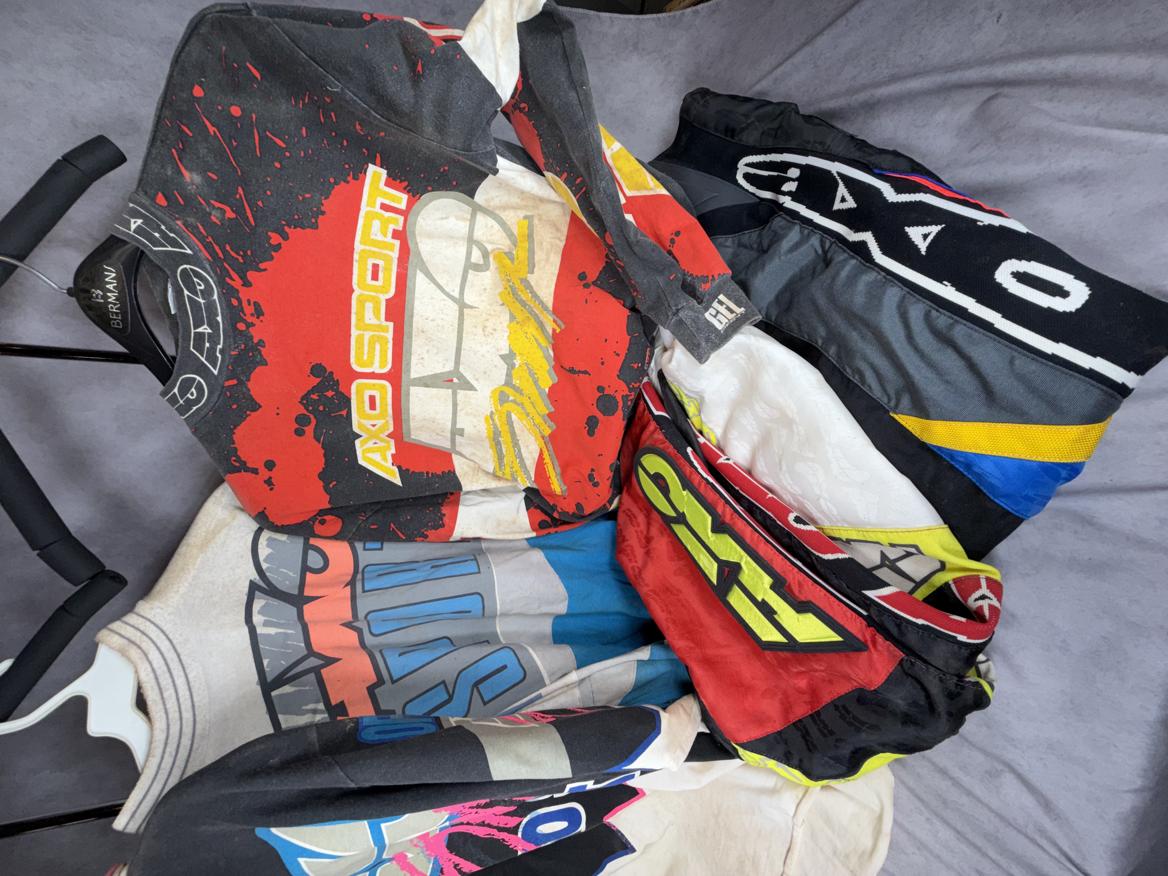 A Collection of Five Vintage AXO Sport Motocross Racing Jerseys and Pants Including Damon Bradshaw Edition Items