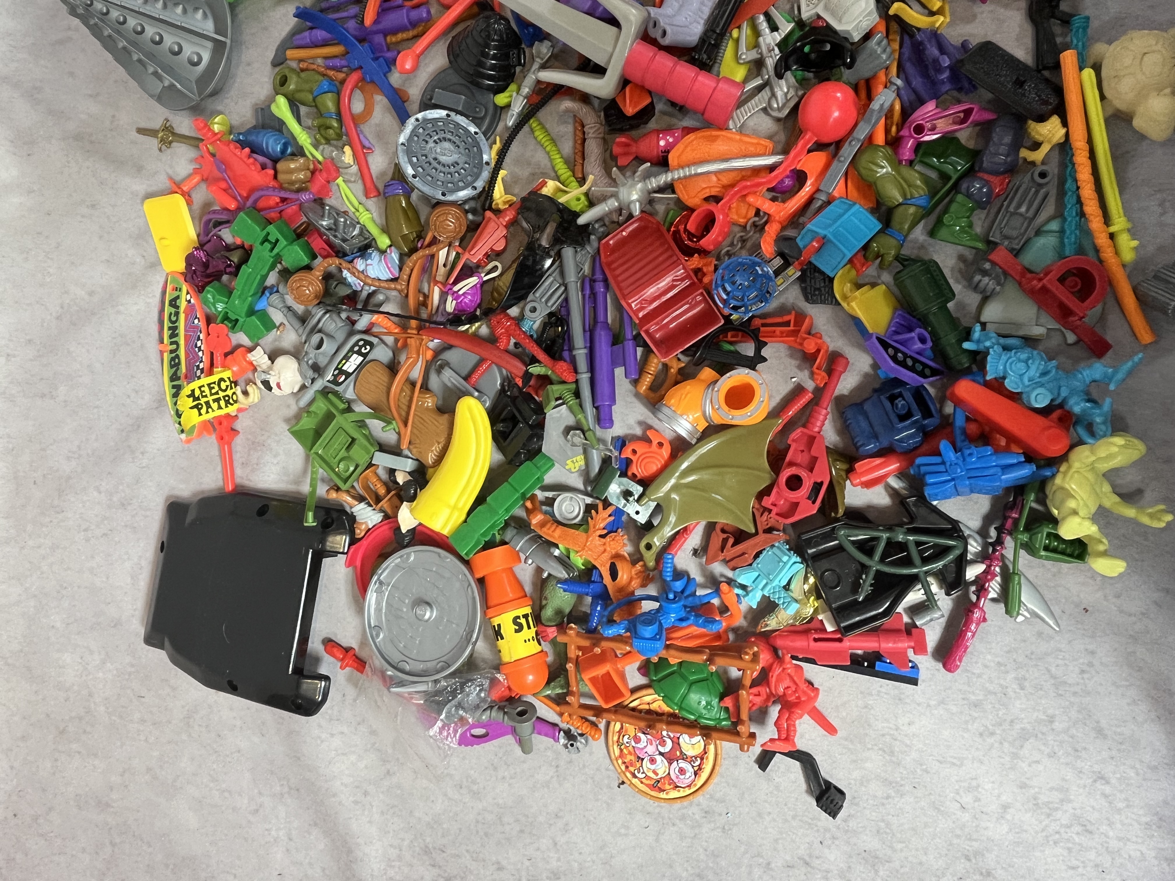 A Collection of Vintage Teenage Mutant Ninja Turtles and Contemporary Action Figure Accessories and Parts