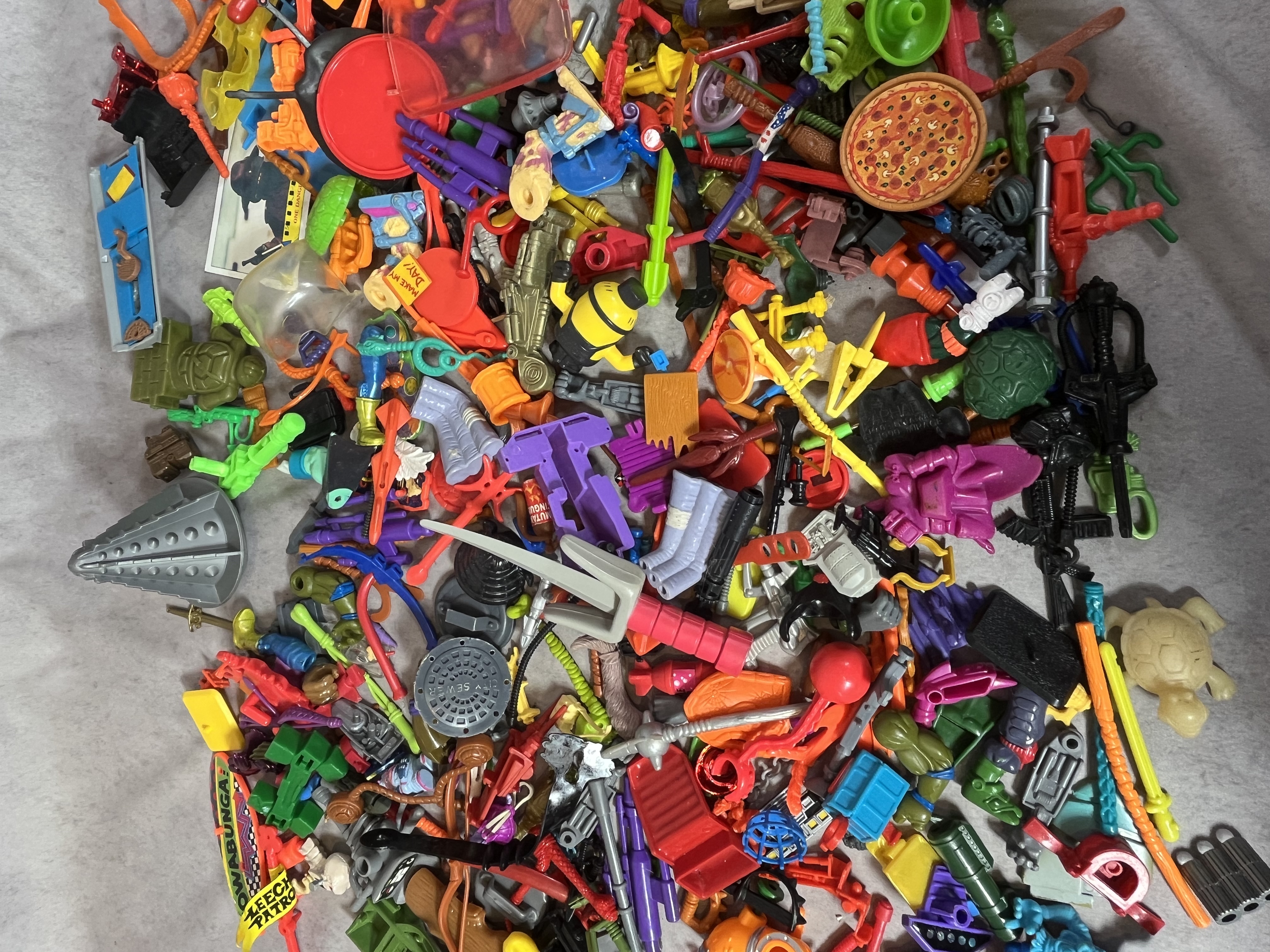 A Collection of Vintage Teenage Mutant Ninja Turtles and Contemporary Action Figure Accessories and Parts