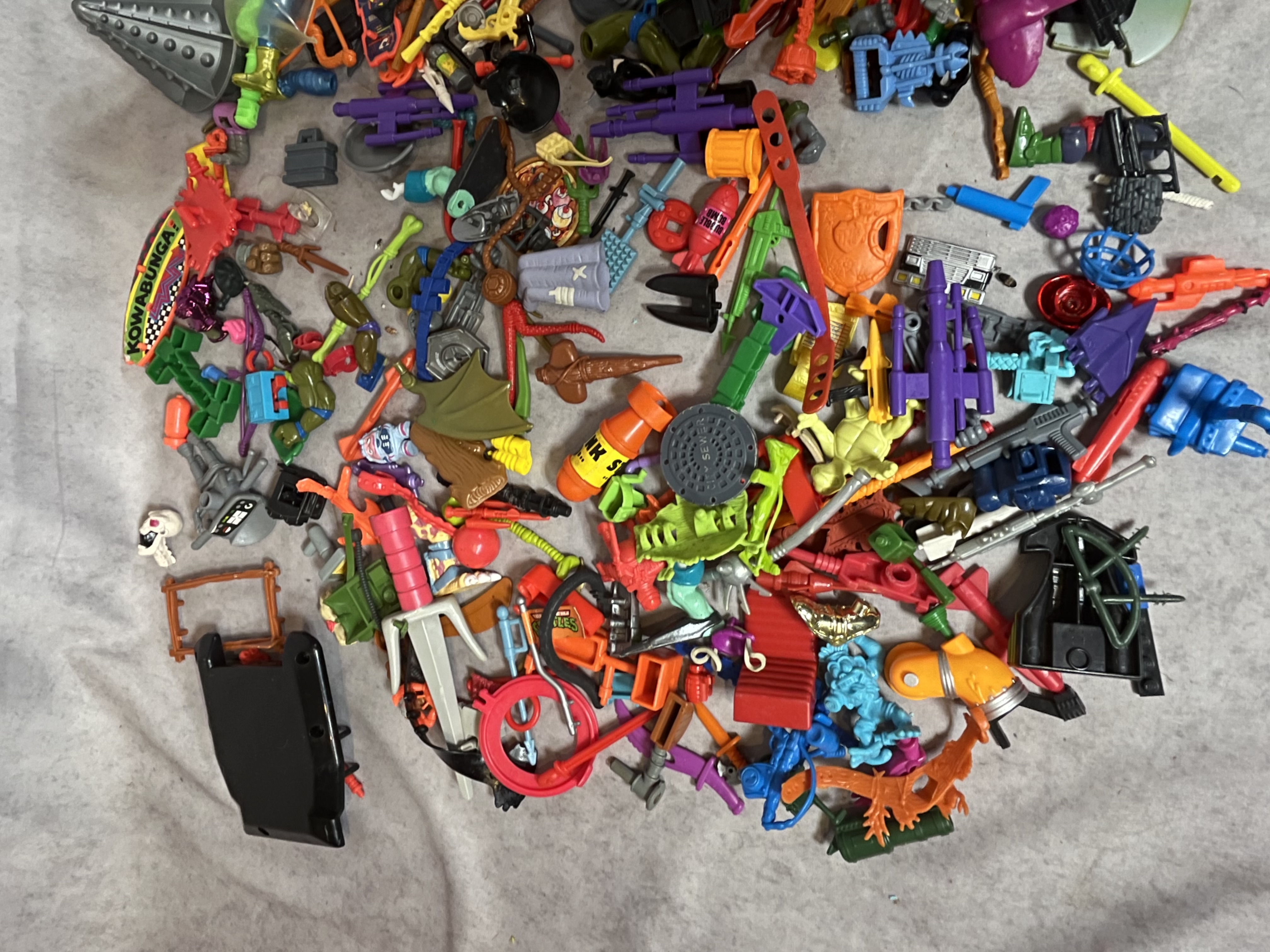 A Collection of Vintage Teenage Mutant Ninja Turtles and Contemporary Action Figure Accessories and Parts