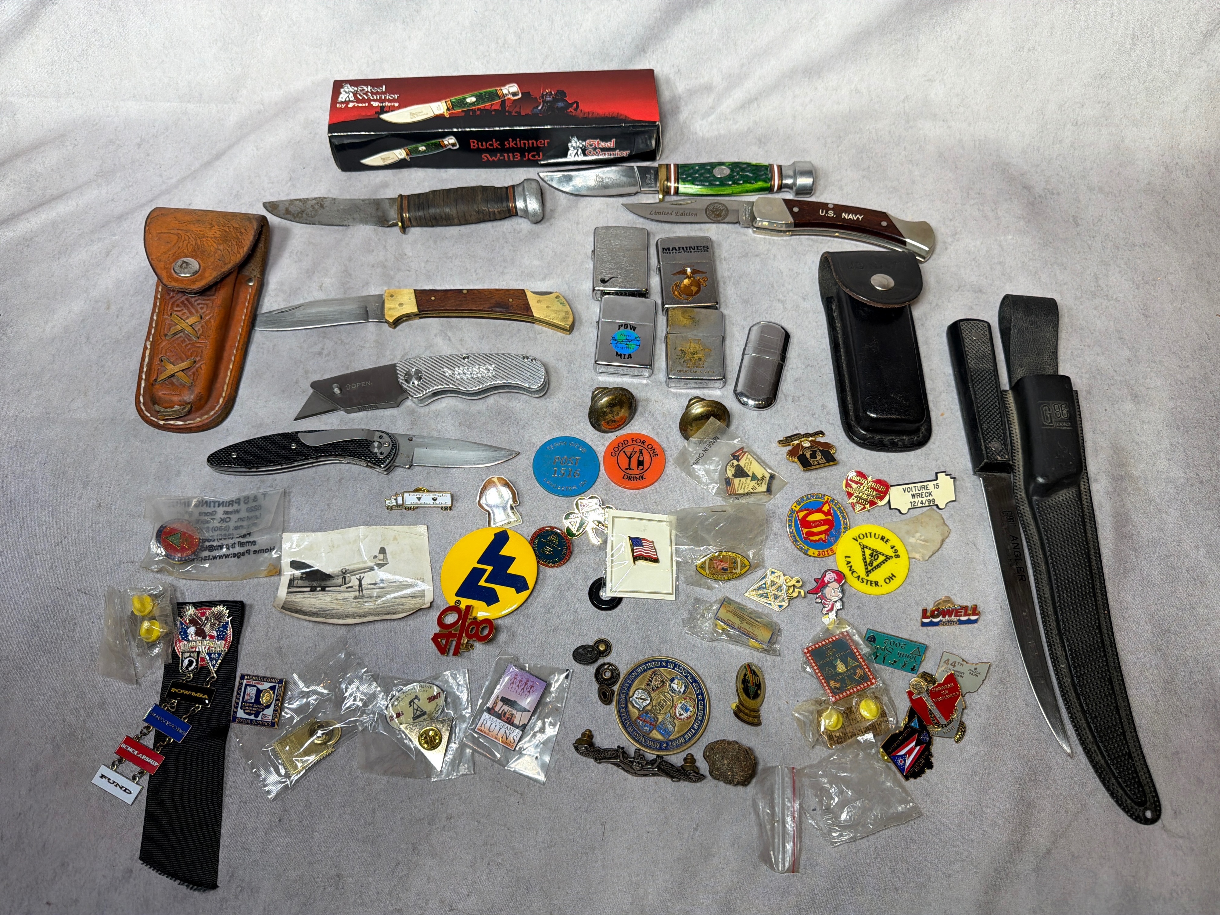 A Collection of Military and Commemorative Folding and Fixed-Blade Knives, Zippo Lighters, and Pins