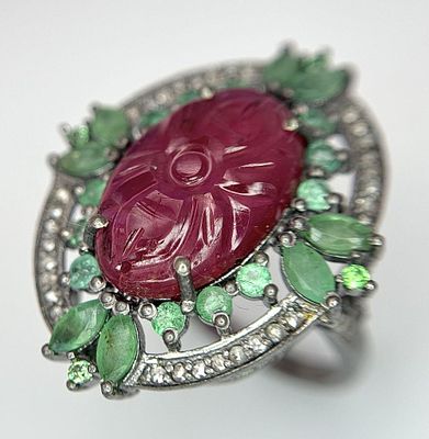 A Ruby, Emerald and Diamond Ring. Central, carved 4ct oval ruby with a floral form emerald 