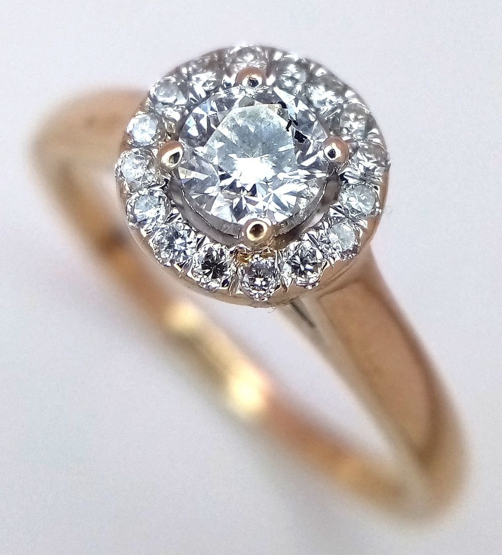 A 18K YELLOW GOLD DIAMOND HALO RING. 0.35CT TOTAL WITH A 0.24CT MAIN CENTRE ROUND BRILLIANT CUT 