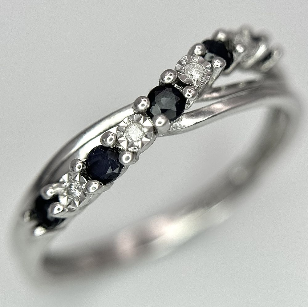 A 9K WHITE GOLD DIAMOND AND SAPPHIRE CROSSOVER RING. 1.5G. SIZE N. SC - 1030.