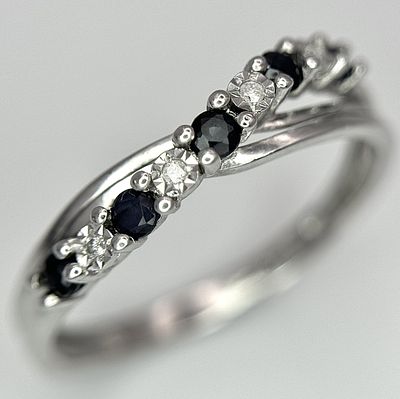 A 9K WHITE GOLD DIAMOND AND SAPPHIRE CROSSOVER RING. 1.5G. SIZE N. SC - 1030.