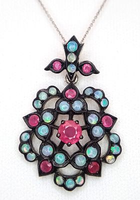 A 9K White Gold, Opal and Ruby Pendant on an 18K White Gold Chain. Pendant - 33mm, 3.9g. Chain 