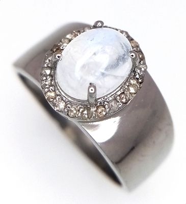 A Moonstone and Diamond Ring set in 925 Silver. Central moonstone cabochon with a diamond 