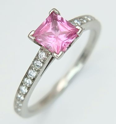 An 18K White Gold, Pink Sapphire and Diamond Ring. A Princess cut 0.5ct pink sapphire with 