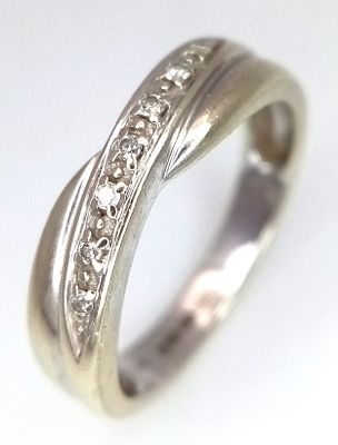 A 9K WHITE GOLD DIAMOND TWIST RING . 2.9gms 0.04ct SIZE M