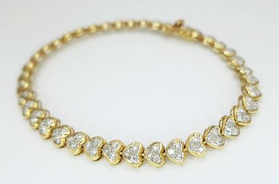An 18K Yellow Gold Diamond Tennis Bracelet in Heart-Shaped Links. Over 100 round brilliant cut 