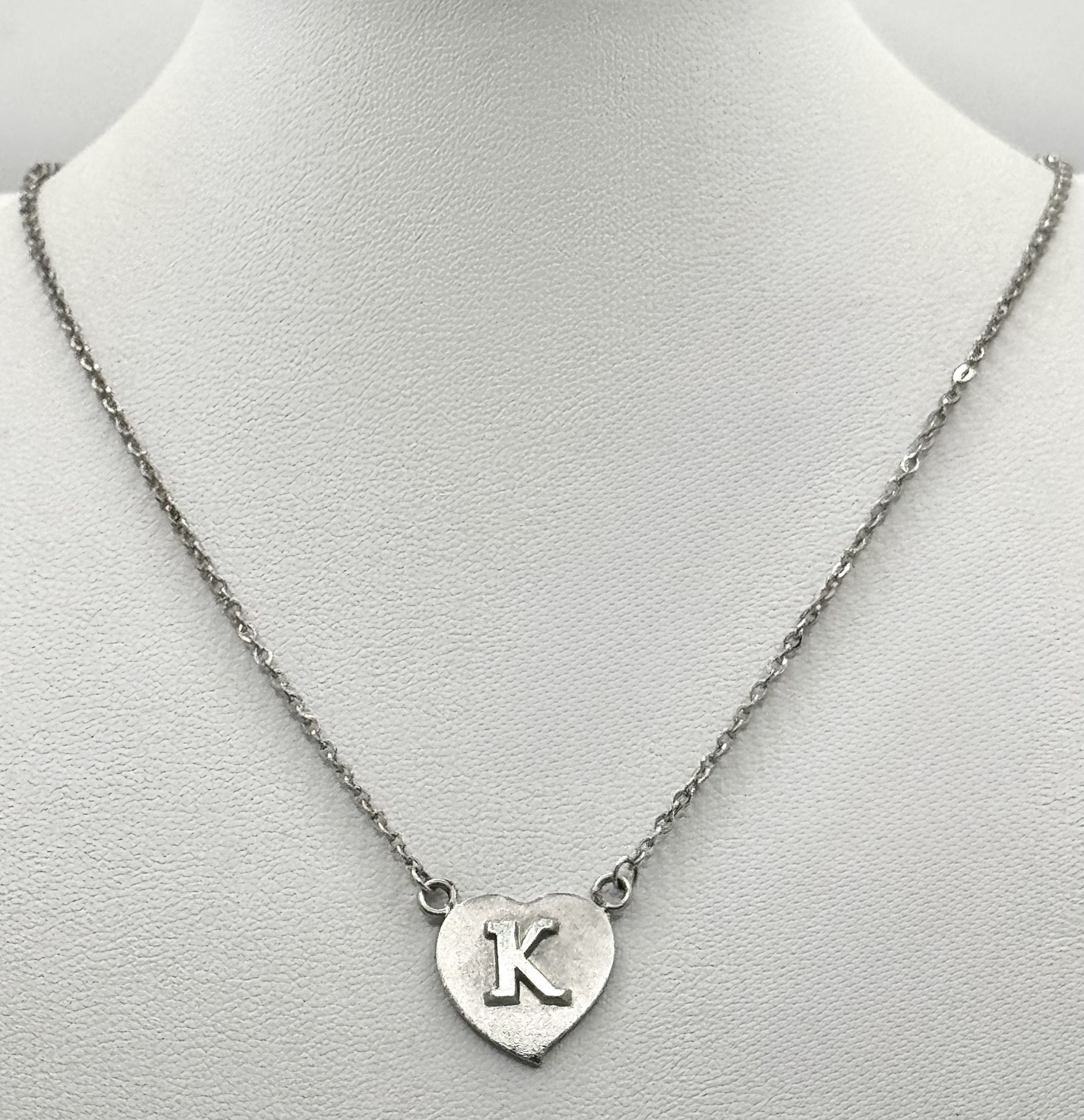 A silver K heart pendant on a silver chain