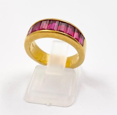 An 18K Yellow Gold Nine-Stone Ruby Band Ring. Baguette-cut vibrant purple-red natural rubies. 